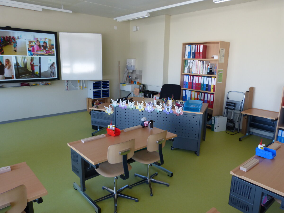 An empty classroom with rows of desks and chairs, light from a window